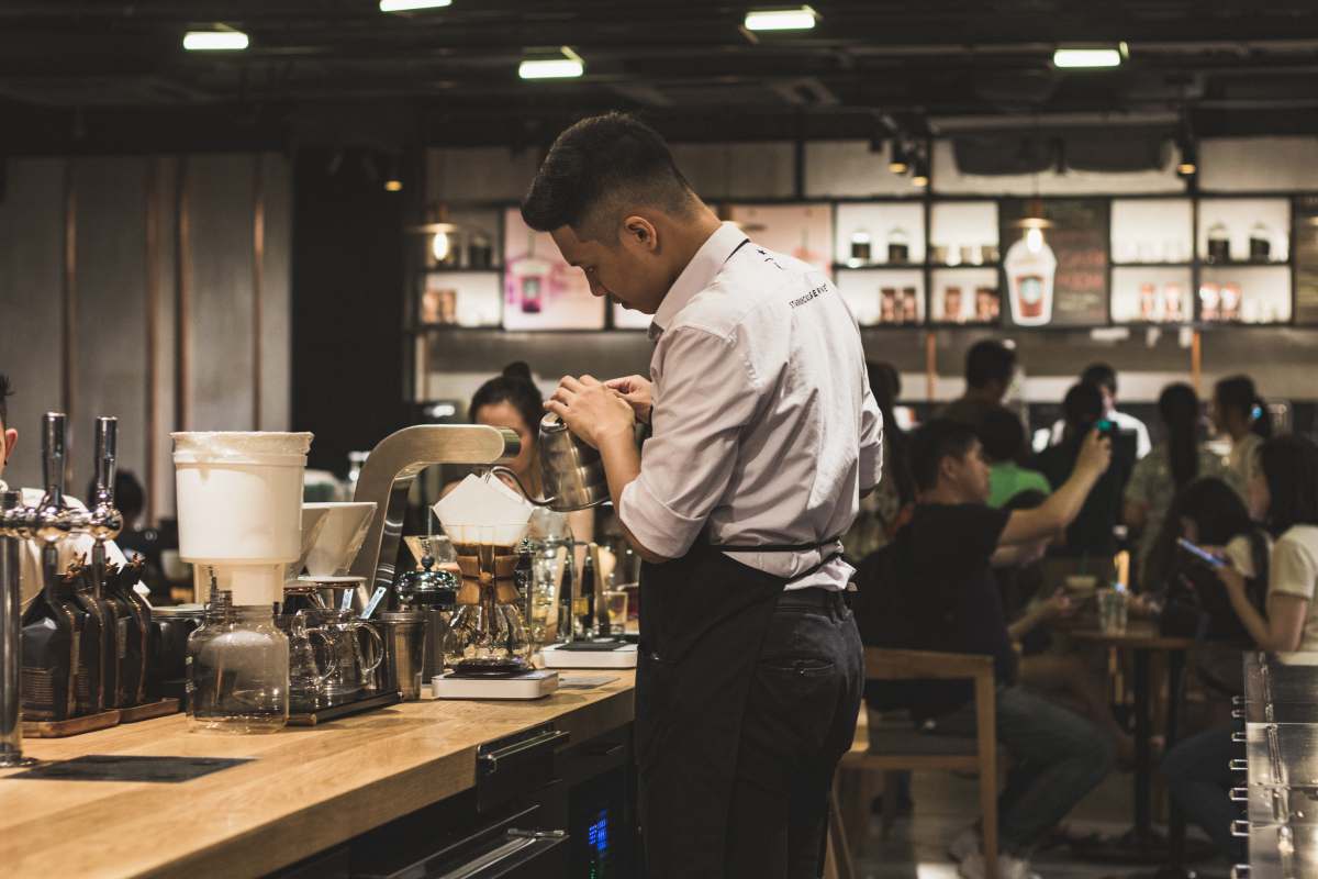 beer bar men's brown dress shirt and black pants making drinks inside a bar cafe